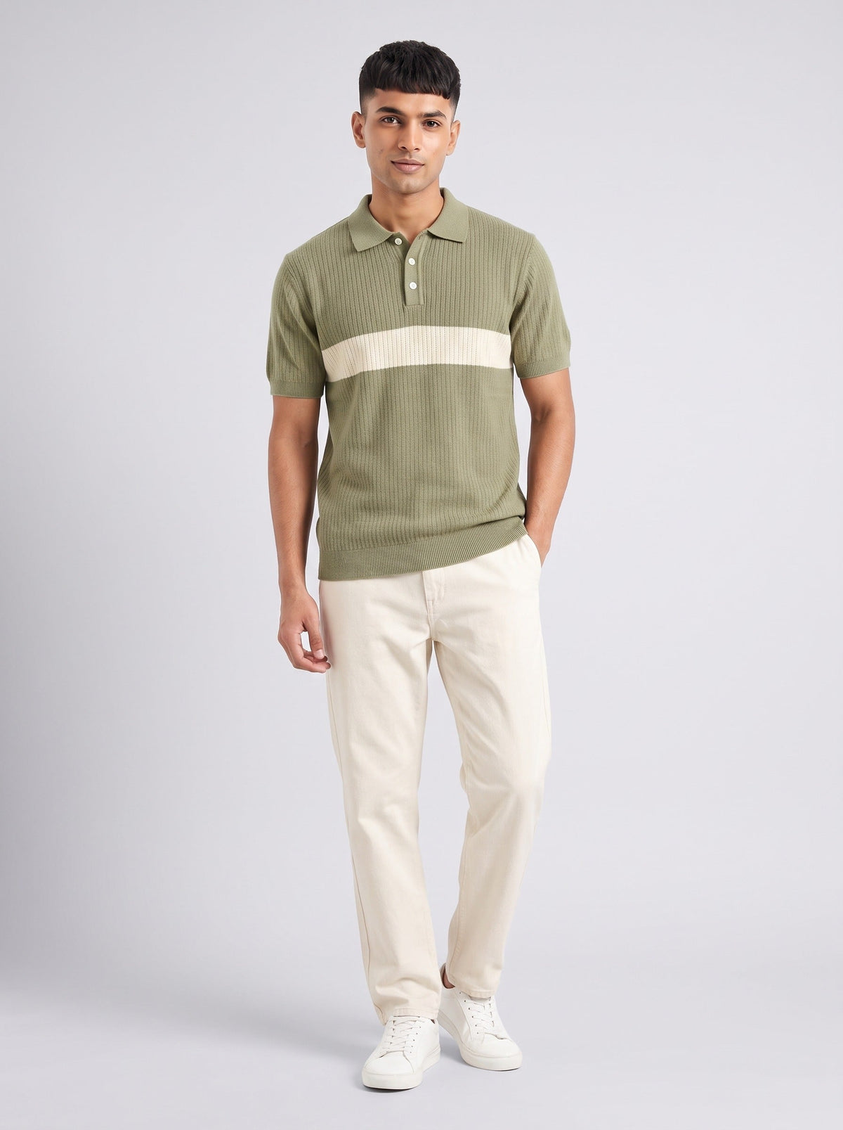 Model wearing The Long Field olive ribbed knit polo with a wide ecru chest band, with cream trousers