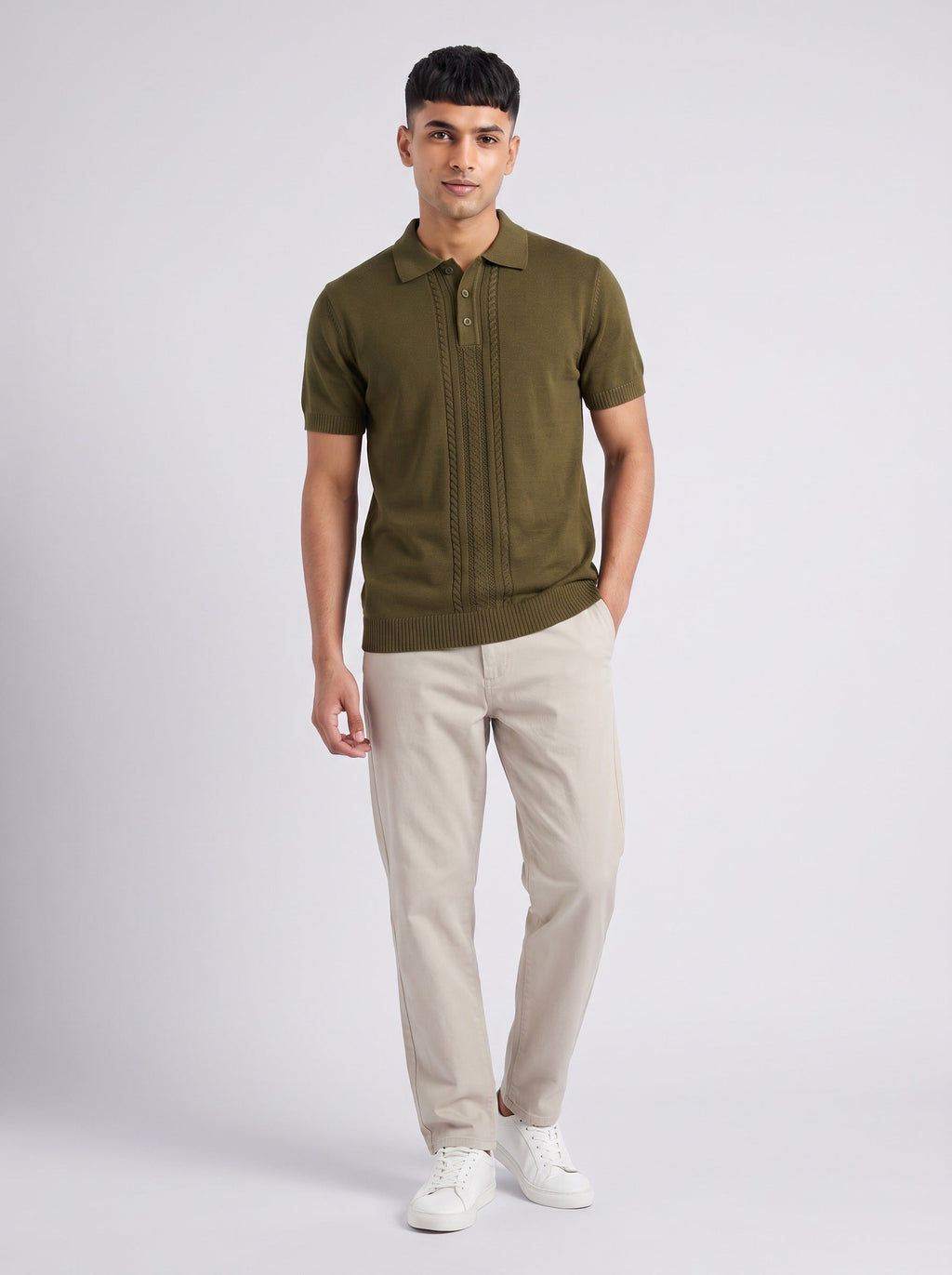Model wearing The Orchard olive knit polo with a full-length centre cable panel, with stone trousers