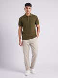 Model wearing The Orchard olive knit polo with a full-length centre cable panel, with stone trousers