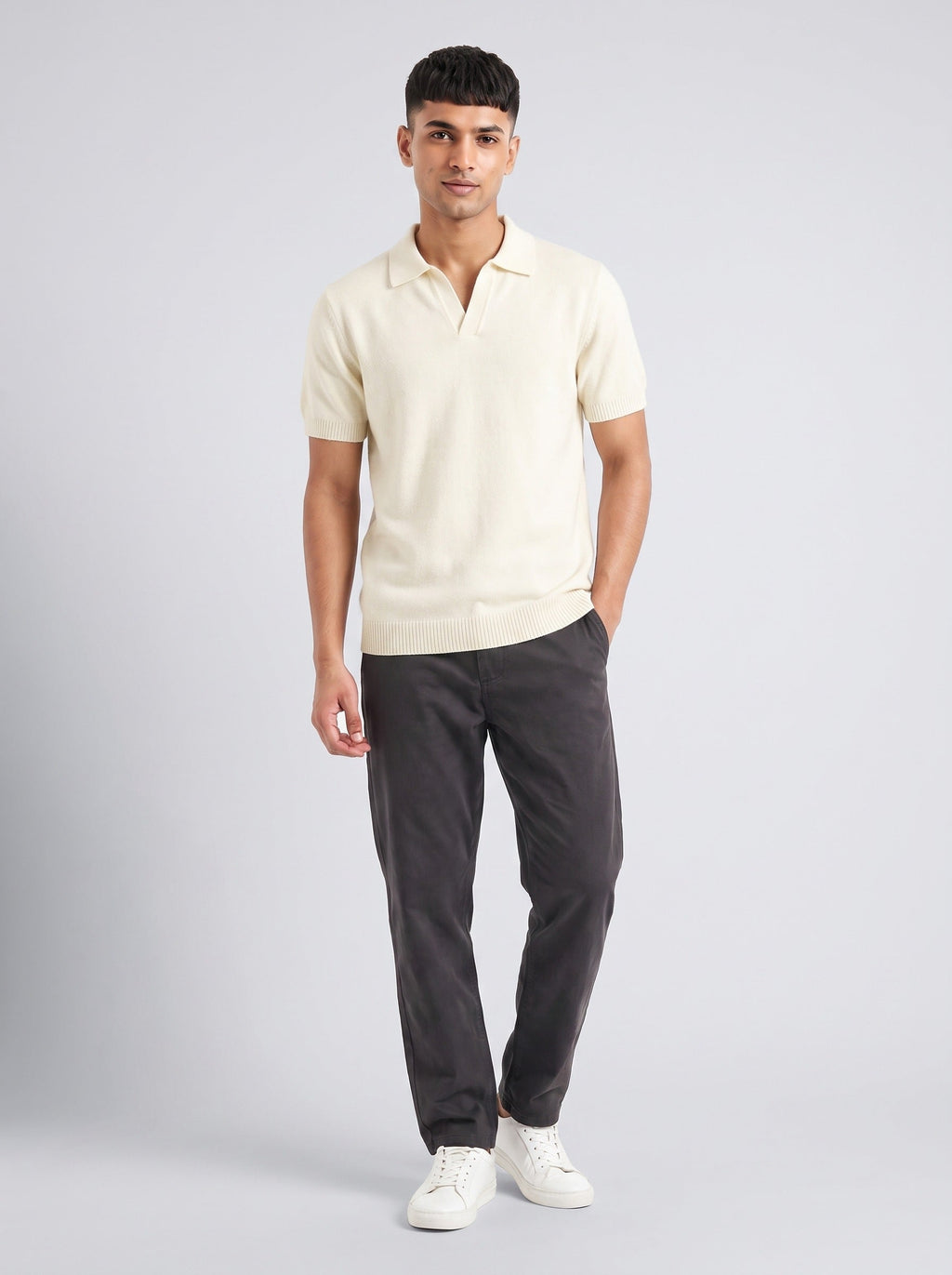 Model wearing The Plain Hour ecru knit polo with an open V collar and no buttons, with charcoal trousers