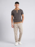 Model wearing The Smoke Room charcoal ribbed knit polo with camel collar, cuffs and hem, with stone trousers