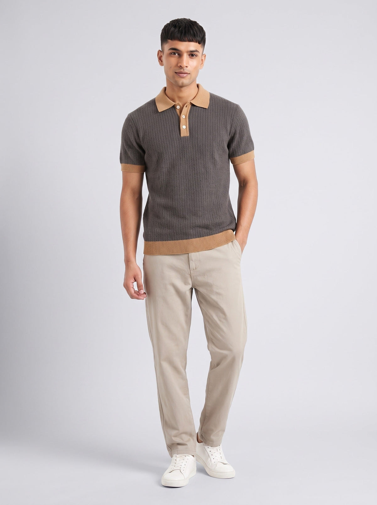 Model wearing The Smoke Room charcoal ribbed knit polo with camel collar, cuffs and hem, with stone trousers