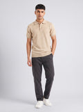 Model wearing The Weather Report flecked oatmeal knit polo with a three-button placket and charcoal trousers